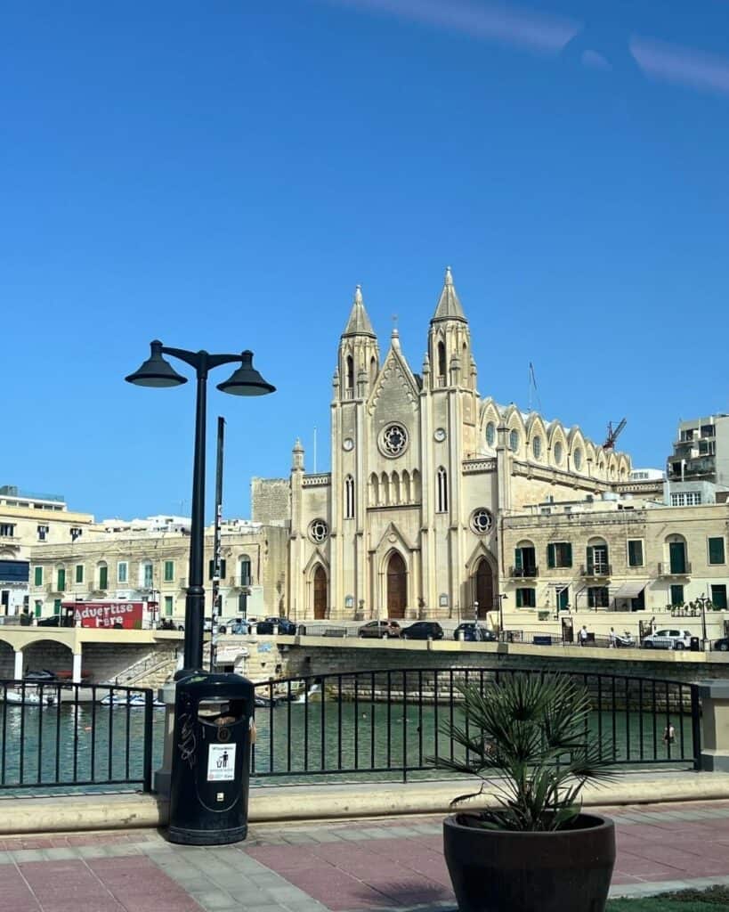 Historische Kirche am Wasser in Malta bei blauem Himmel – Arbeiten von der Sonne aus und ortsunabhängiges Online-Business.