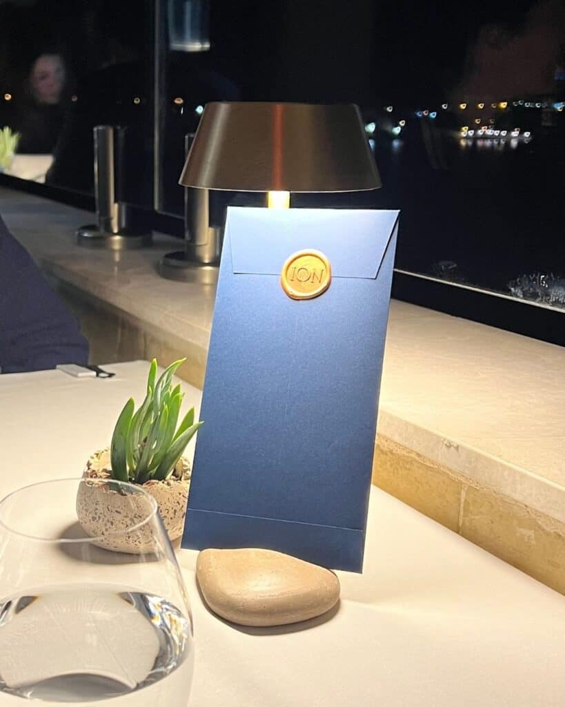 Stimmungsvolle Tischszene am Abend mit Lampe und Menükarte in einem Restaurant auf Malta – Alltag und Lebensqualität beim ortsunabhängigen Arbeiten.